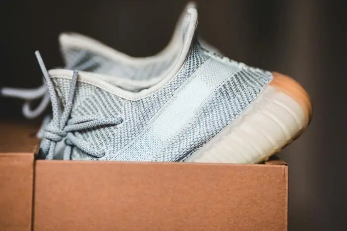 Pale knit sneaker resting in a cardboard box, ready for a carry on sneaker travel bag.