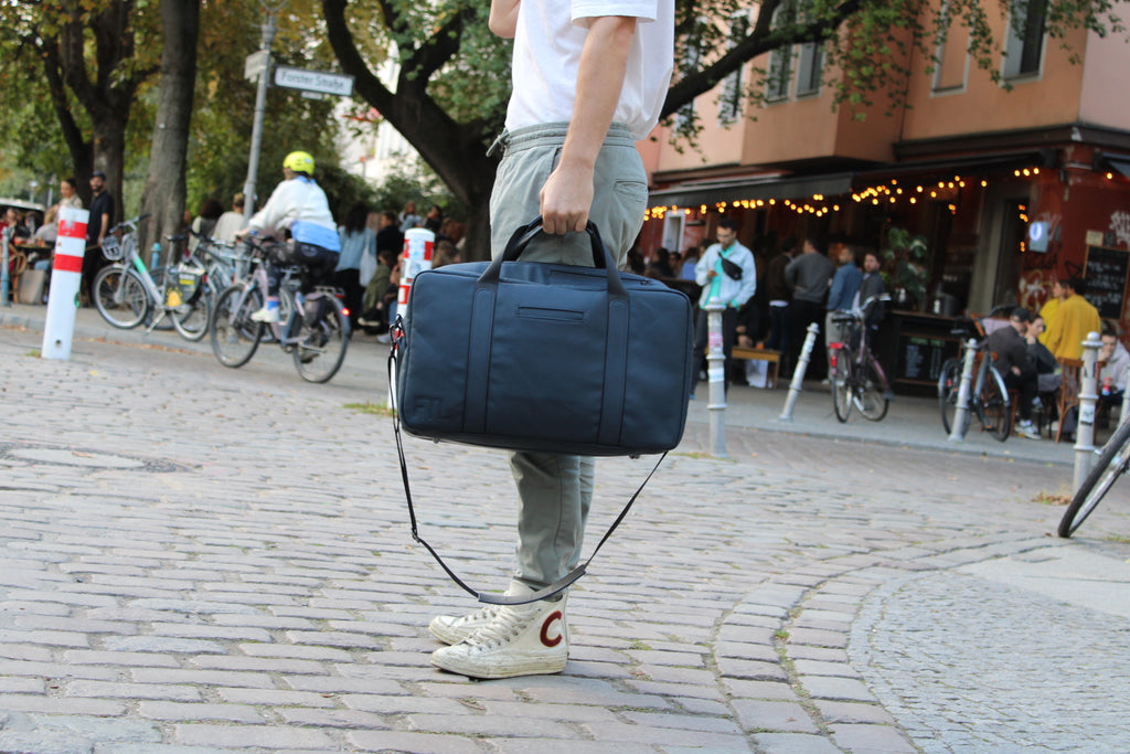 Carry on garment duffel bag in navy with shoulder strap, ideal for travel and city commutes with a sleek silhouette.