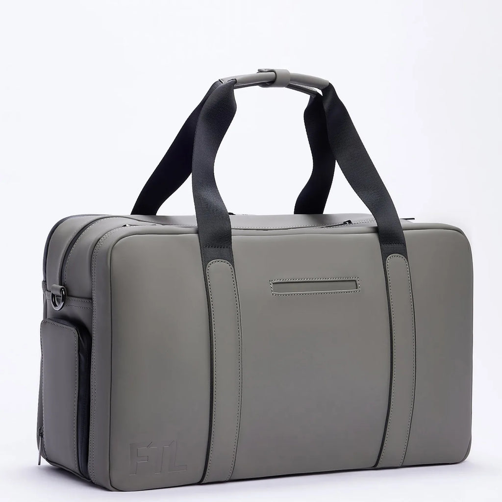 Gray FTL Max duffle bag with black carry straps and embossed logo, side angle.