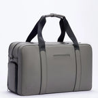 Gray FTL Max duffle bag with black carry straps and embossed logo, side angle.