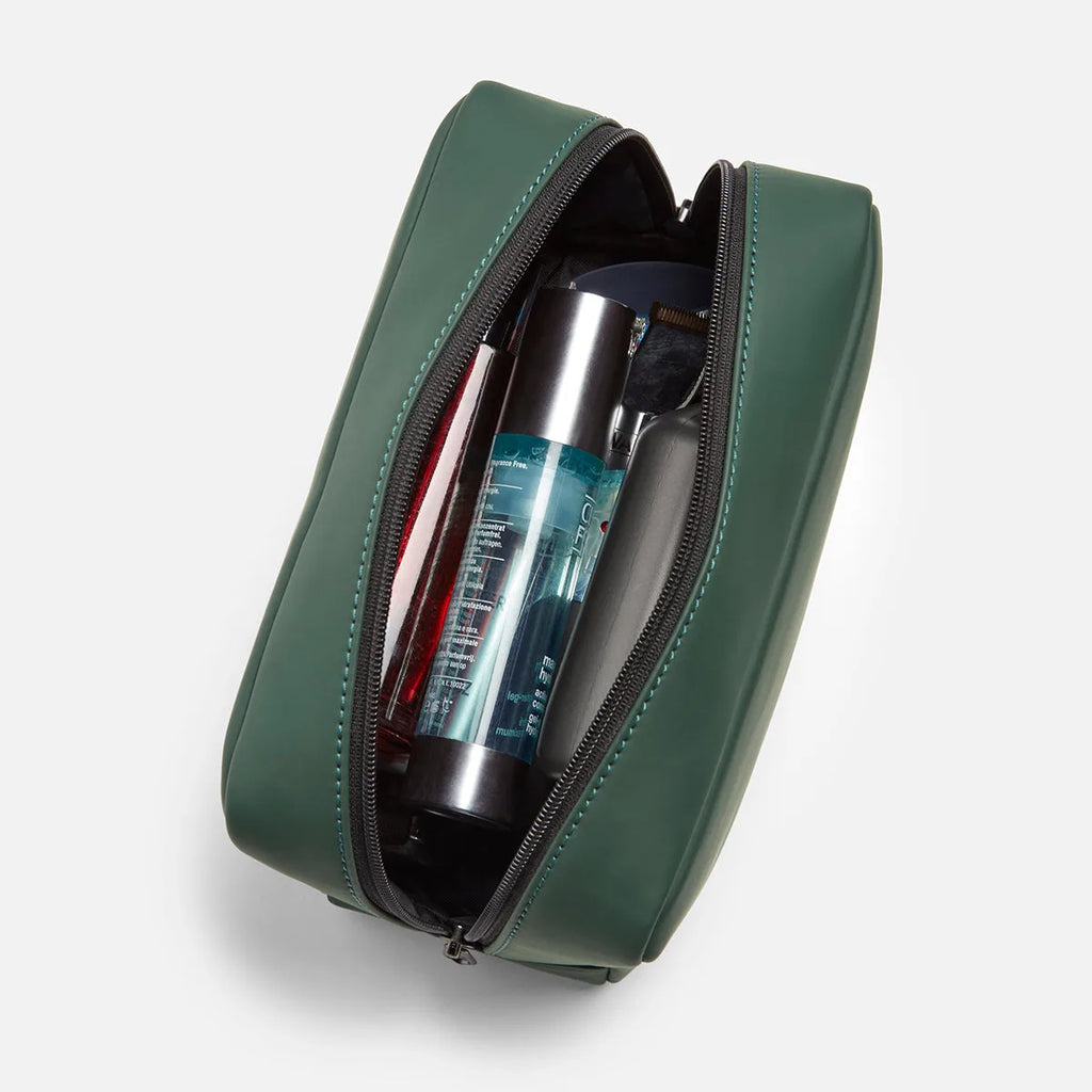 Green FTL dopp kit unzipped and packed with toiletry bottles and grooming supplies.
