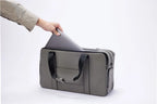 Hand sliding a laptop into the padded sleeve of a stone grey FTL Pro duffel.