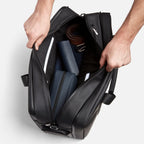 Hands opening a black FTL Pro duffel bag packed with a belt and toiletry cases.