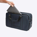 Navy blue FTL Pro laptop duffel bag with a laptop sliding into its padded sleeve.