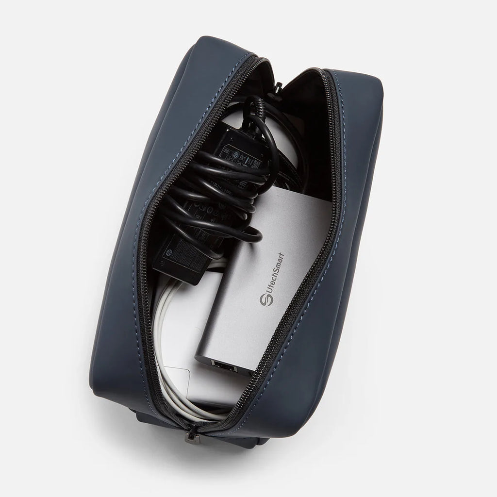 Navy blue FTL tech organizer open, holding a charging brick, coiled cables, and a USB hub.