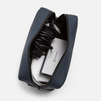 Navy blue FTL tech organizer open, holding a charging brick, coiled cables, and a USB hub.